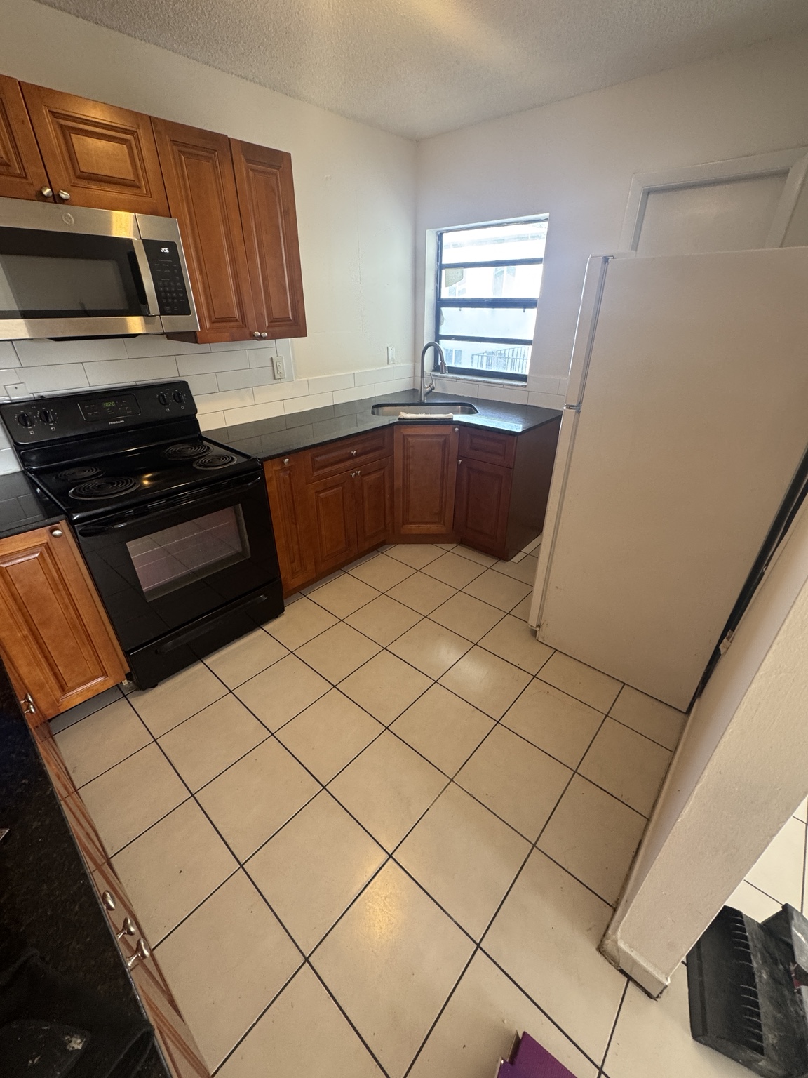 Kitchen before installation with original light square tile flooring.