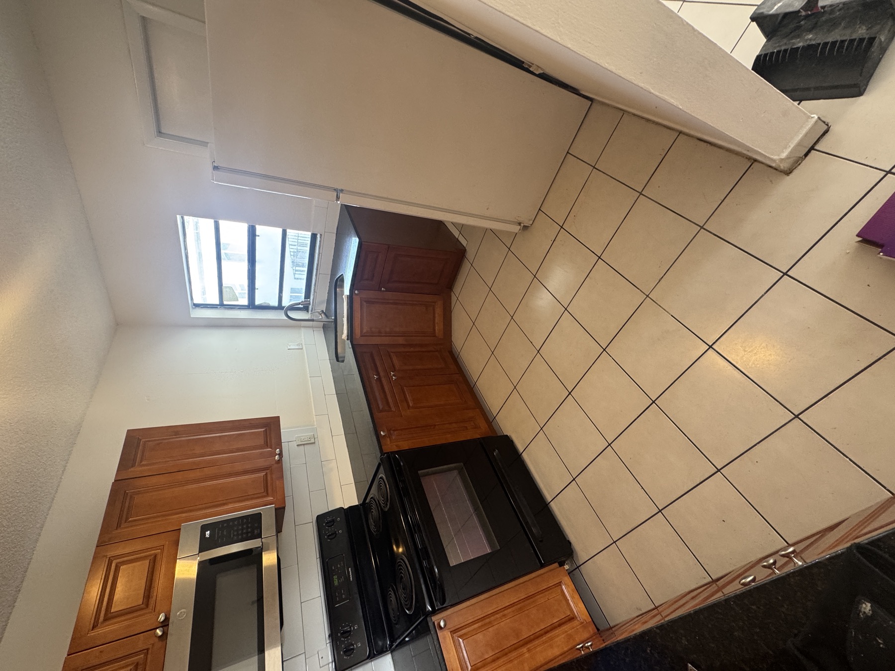 Apartment kitchen with existing white ceramic tile floor before vinyl plank installation in Kendall West