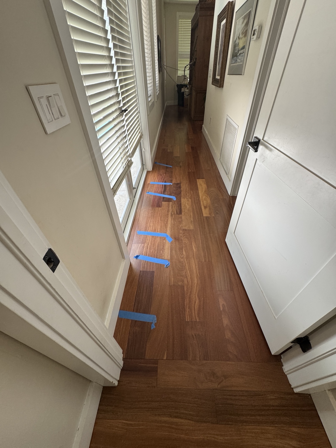 Hardwood floor planks marked with blue tape during repair assessment.