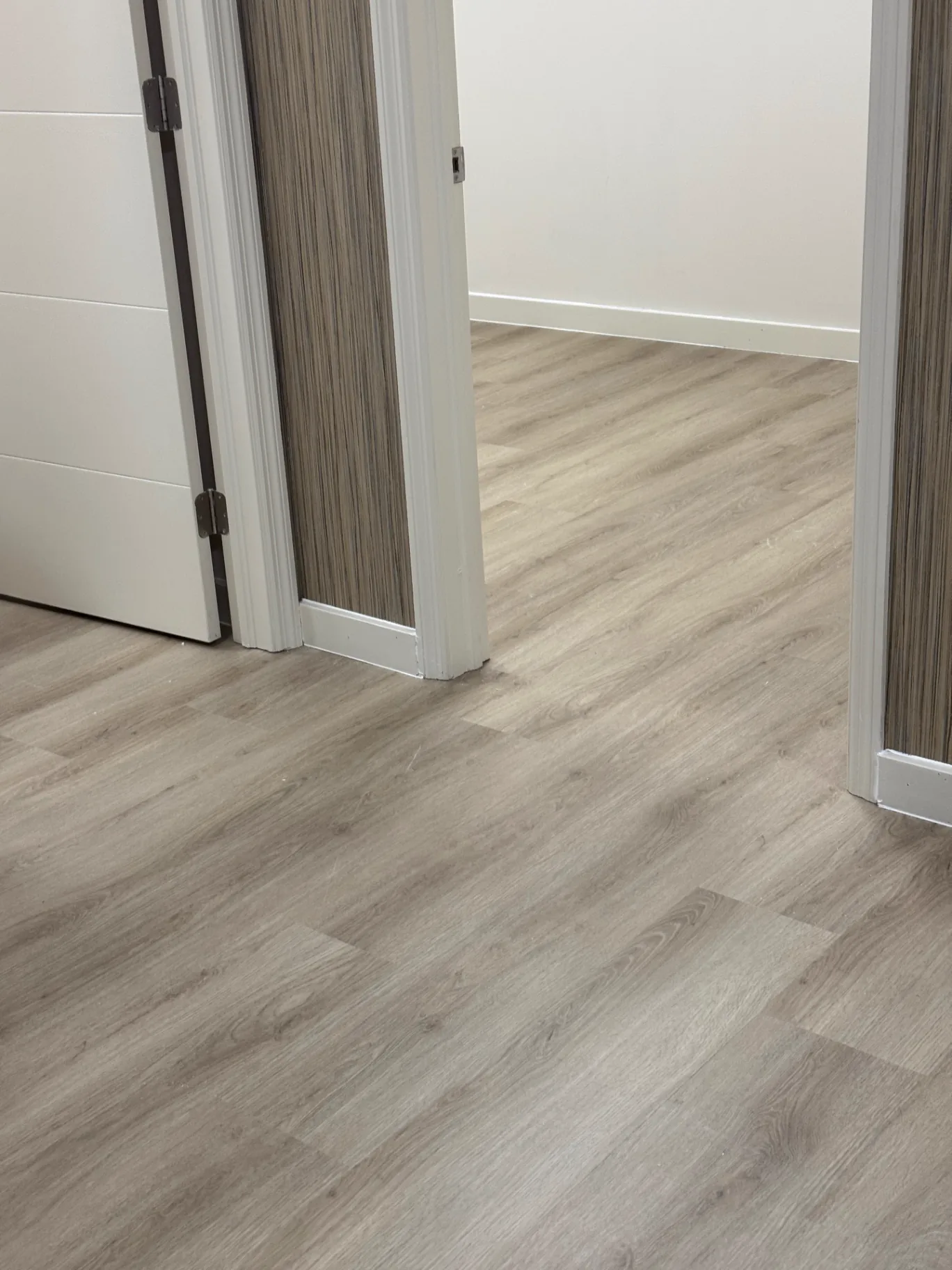 Close-up detail of the lighter warm oak wood-look commercial flooring installed by Colors Wood Floor Corp near a doorway.