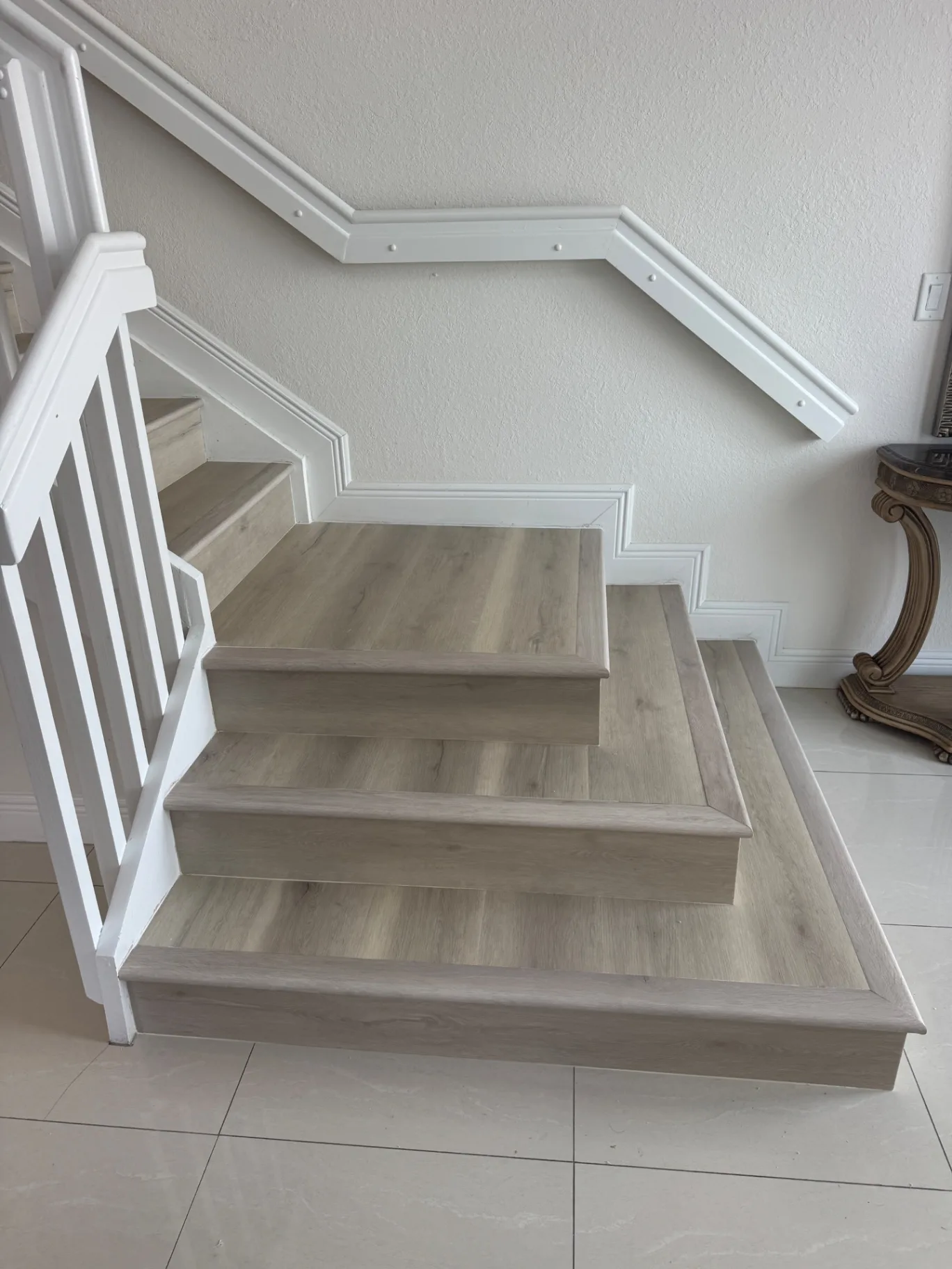 Completed lower steps with clean bullnose edges and continuous light gray wood-look finish.