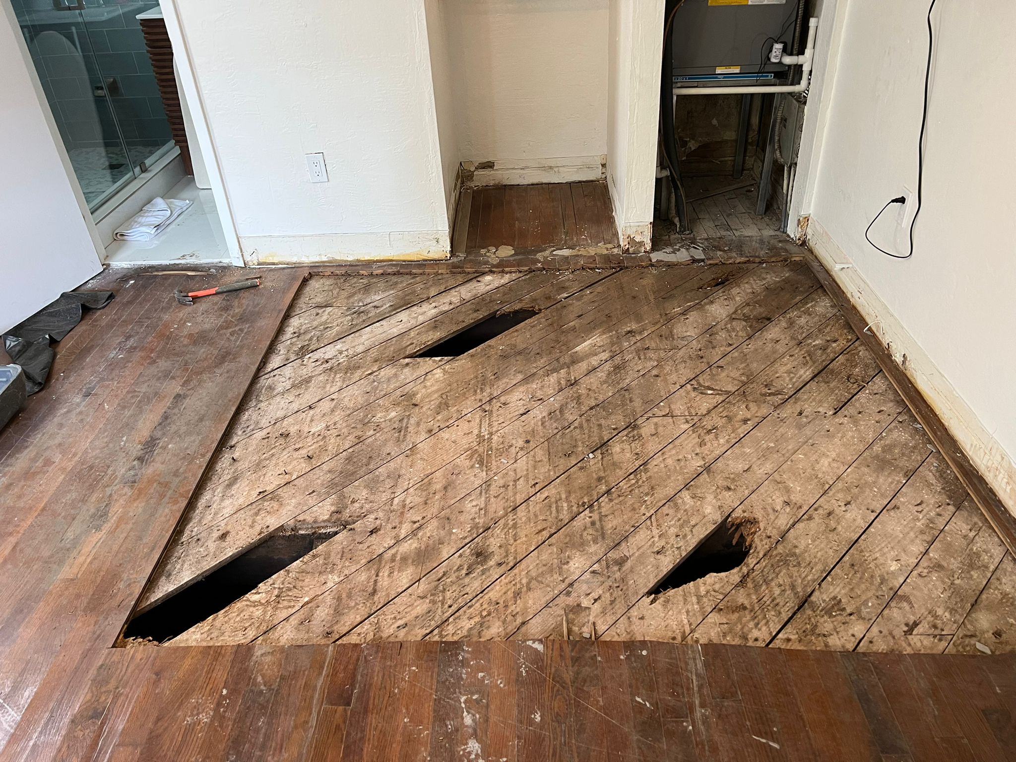 Damaged wood subfloor with structural holes exposed after removing old Red Oak hardwood flooring in a Miami Beach home