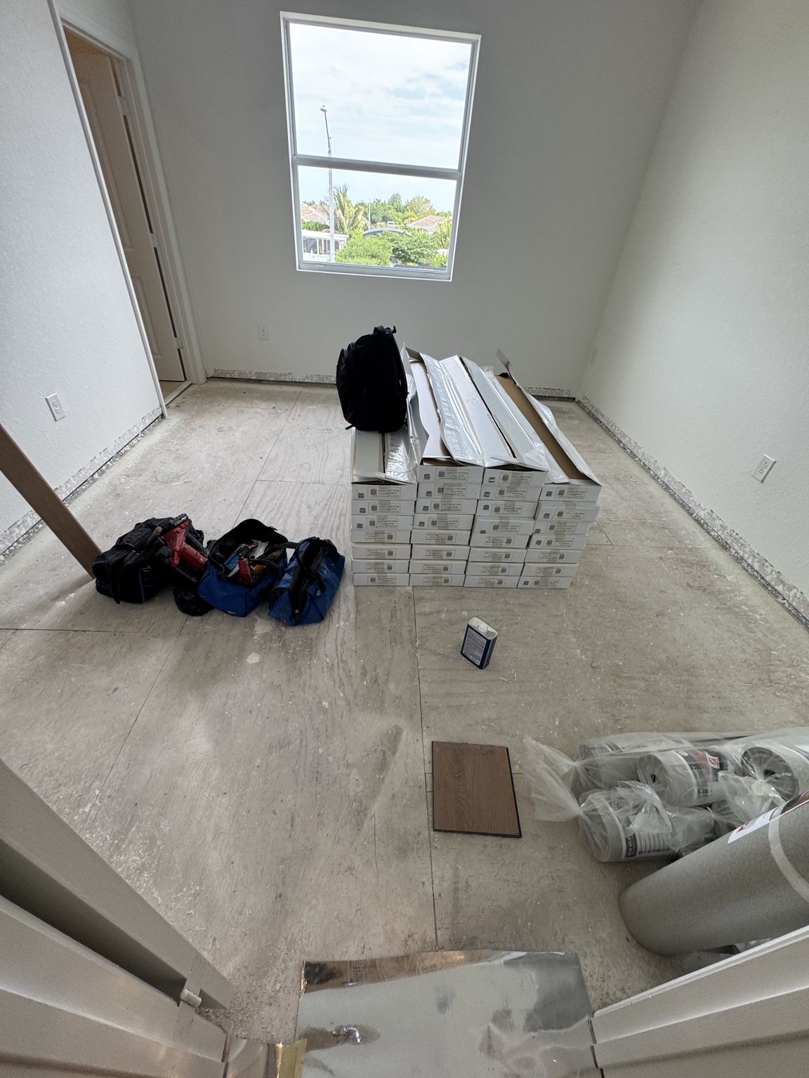 Warm oak laminate flooring boxes and installation tools staged in a bedroom