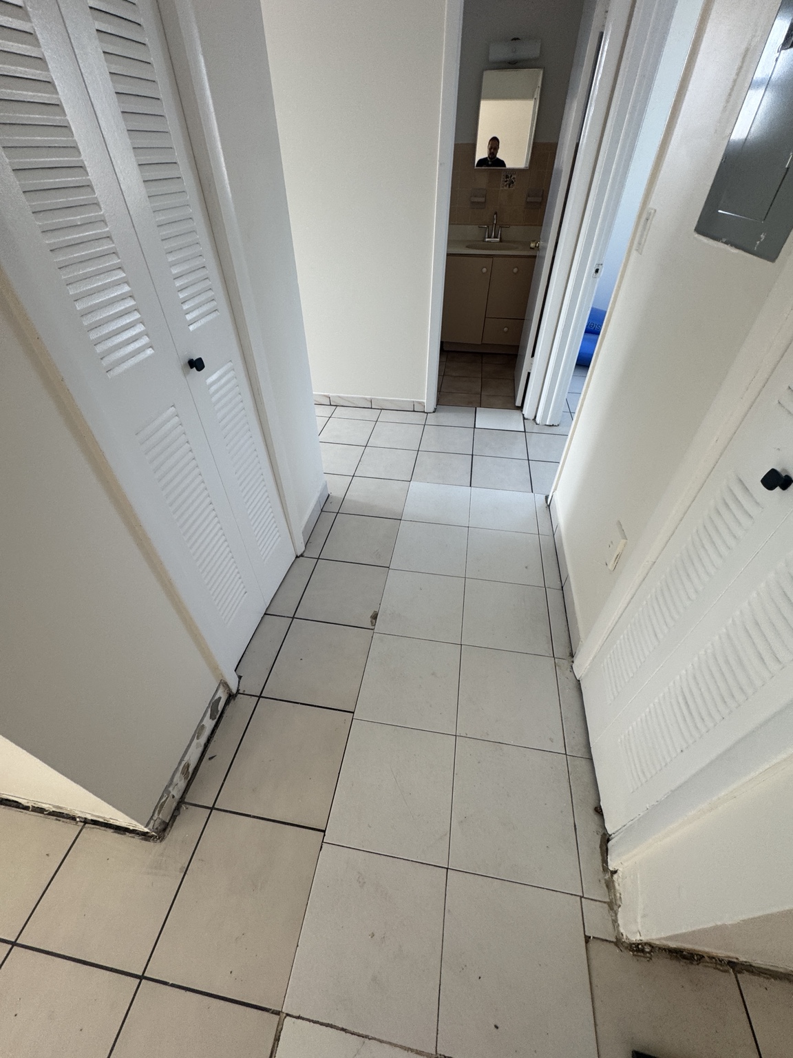 Hallway before installation with existing light tile flooring and baseboards removed during preparation.