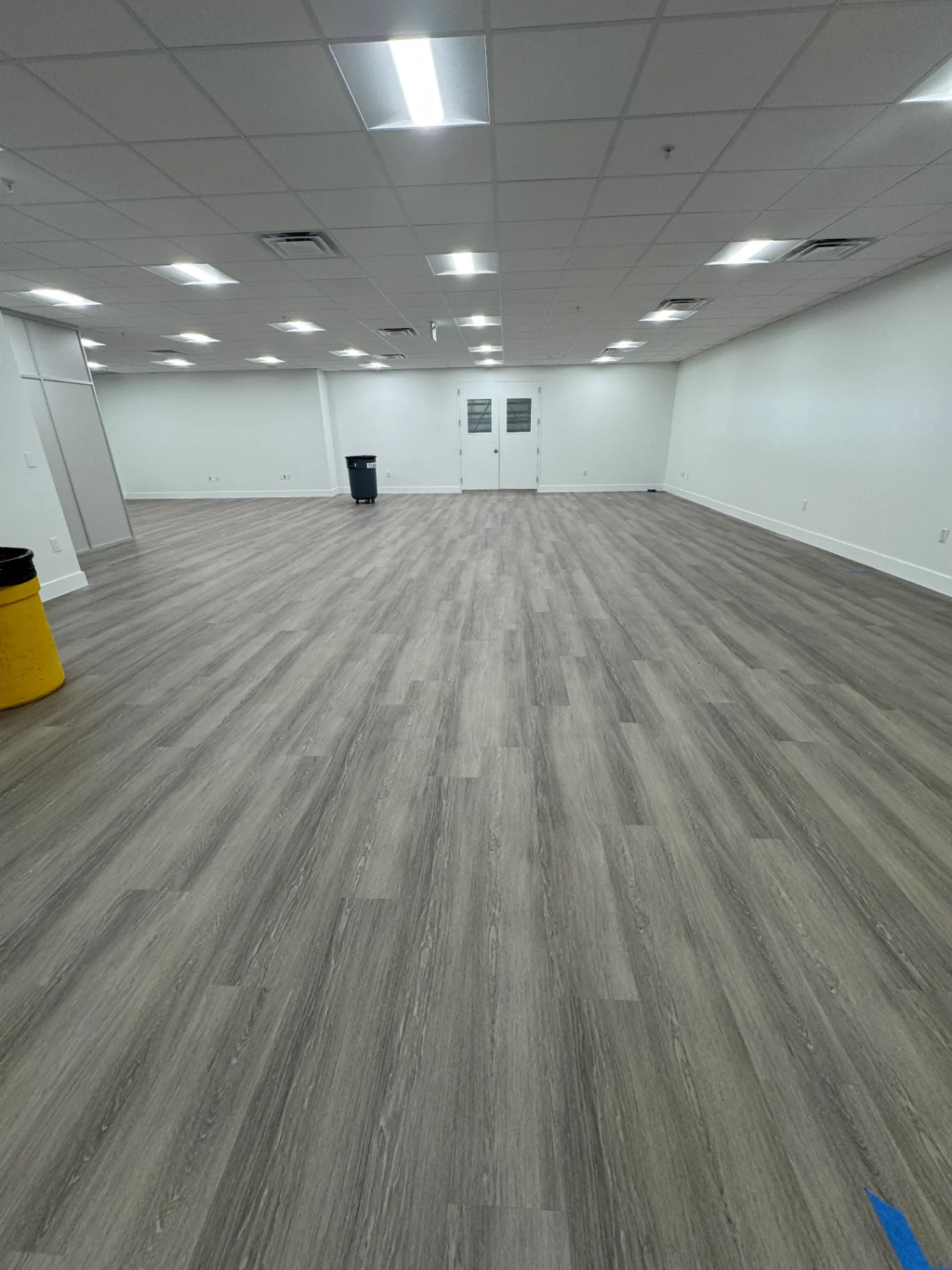 Large open Miami commercial space with warm-gray wood-look flooring completed by Colors Wood Floor Corp before furniture install.