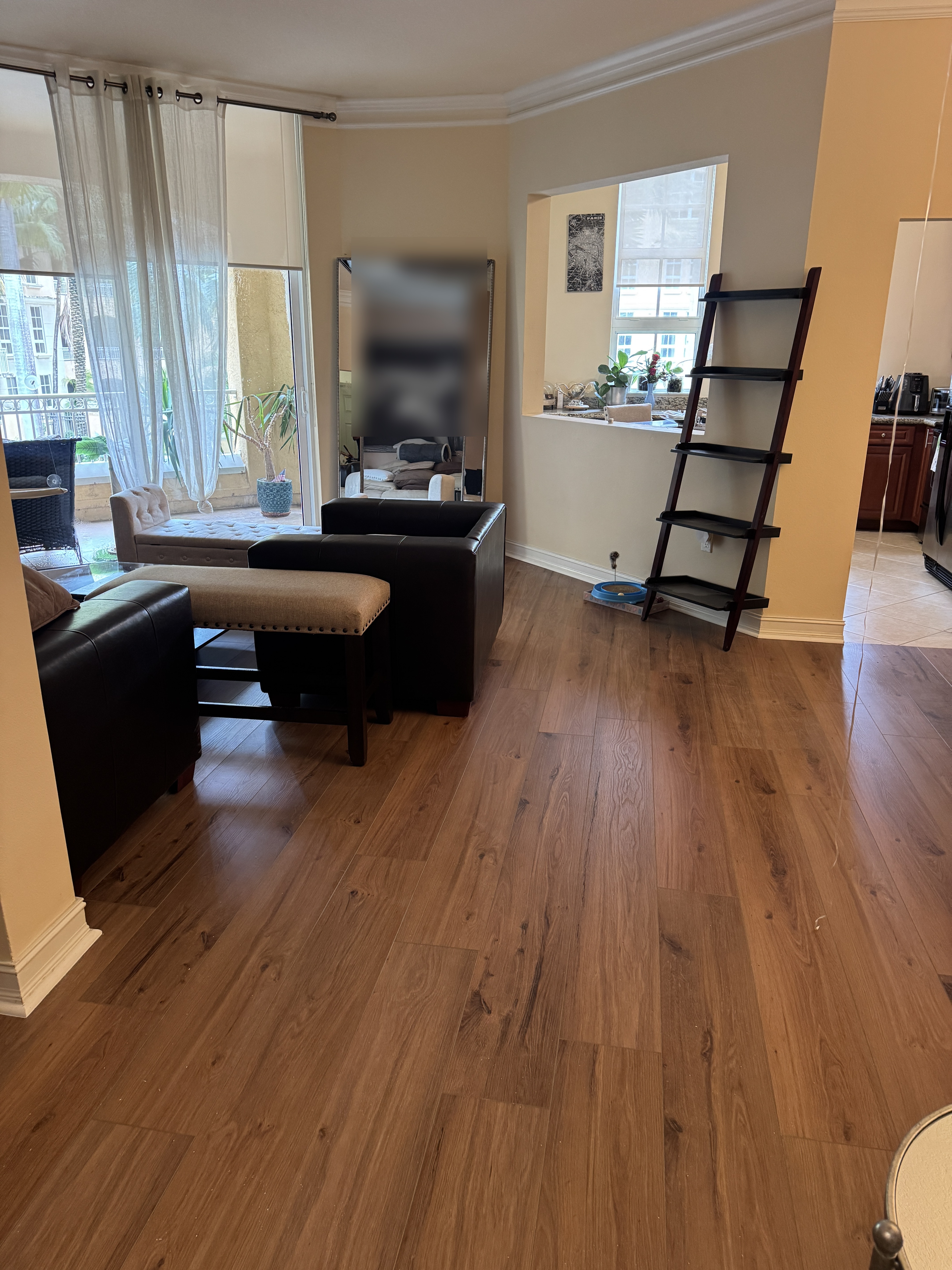 Angled hallway view of completed vinyl wood-look flooring beside the living room and kitchen area in an Aventura, FL condo.