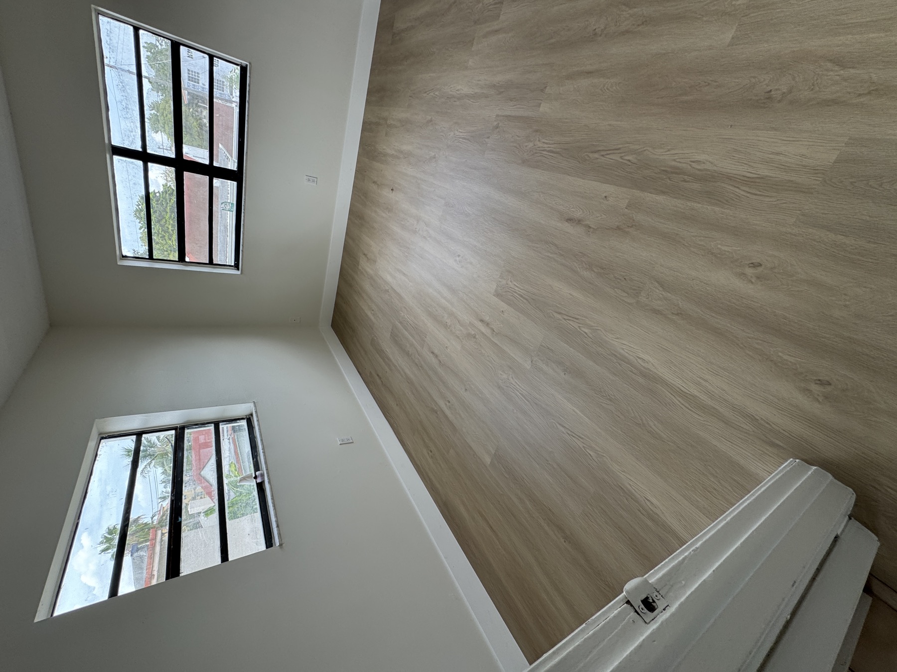 Bedroom with light vinyl plank flooring installed over existing tile