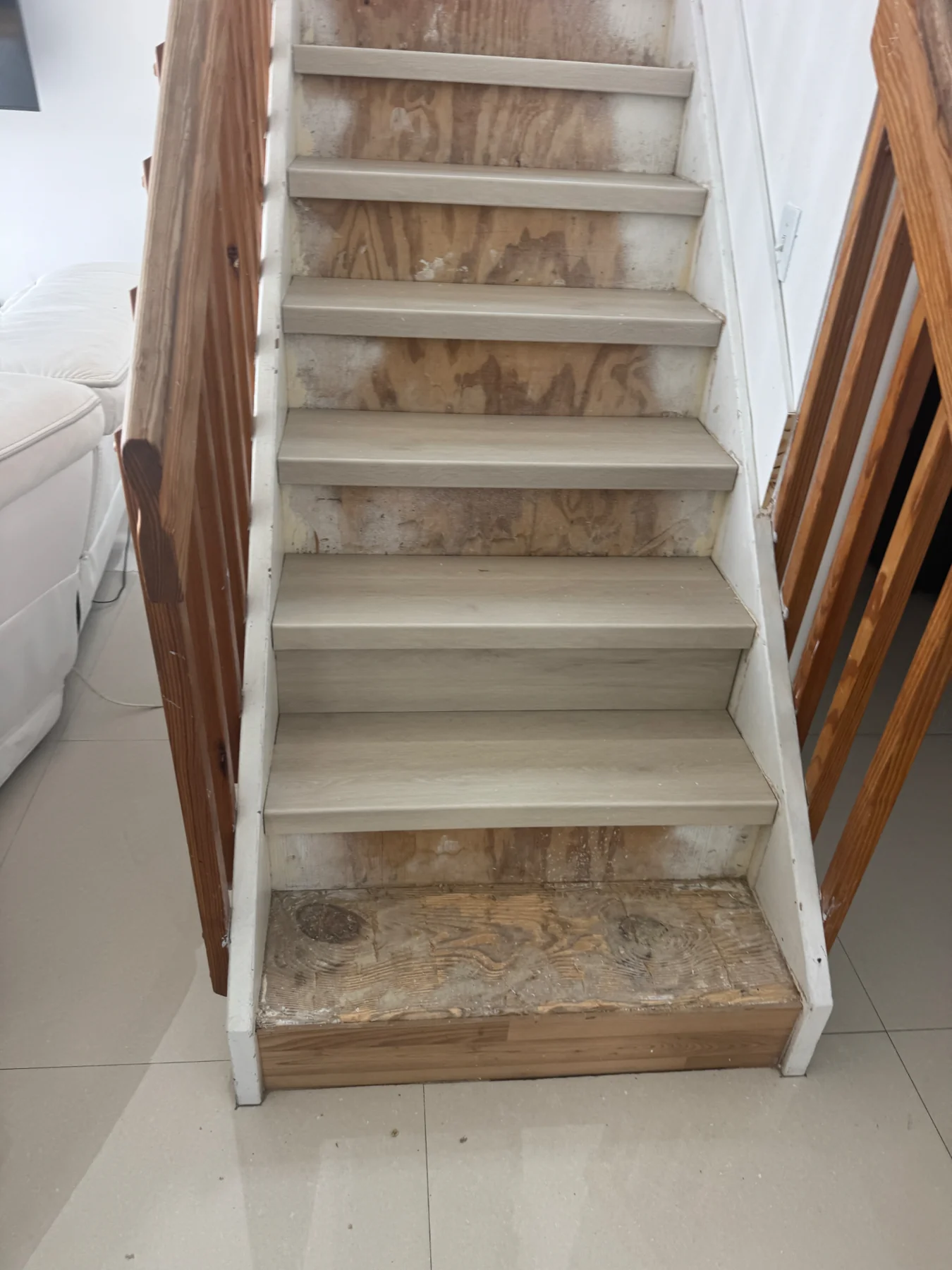 Supporting view of the staircase during installation — treads in place, lower area still being prepared.
