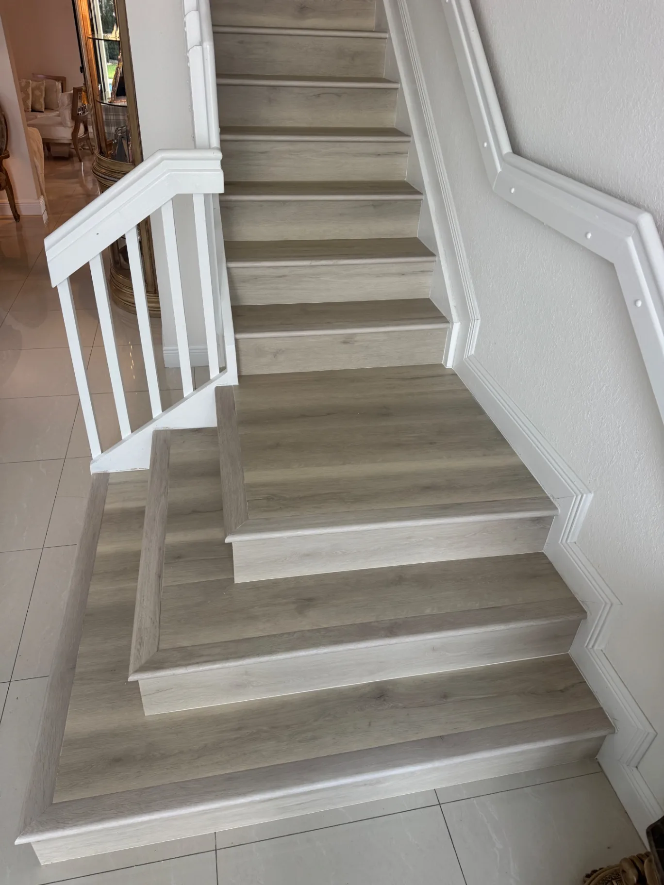 Completed staircase seen from the top landing looking down — continuous light gray wood-look finish.