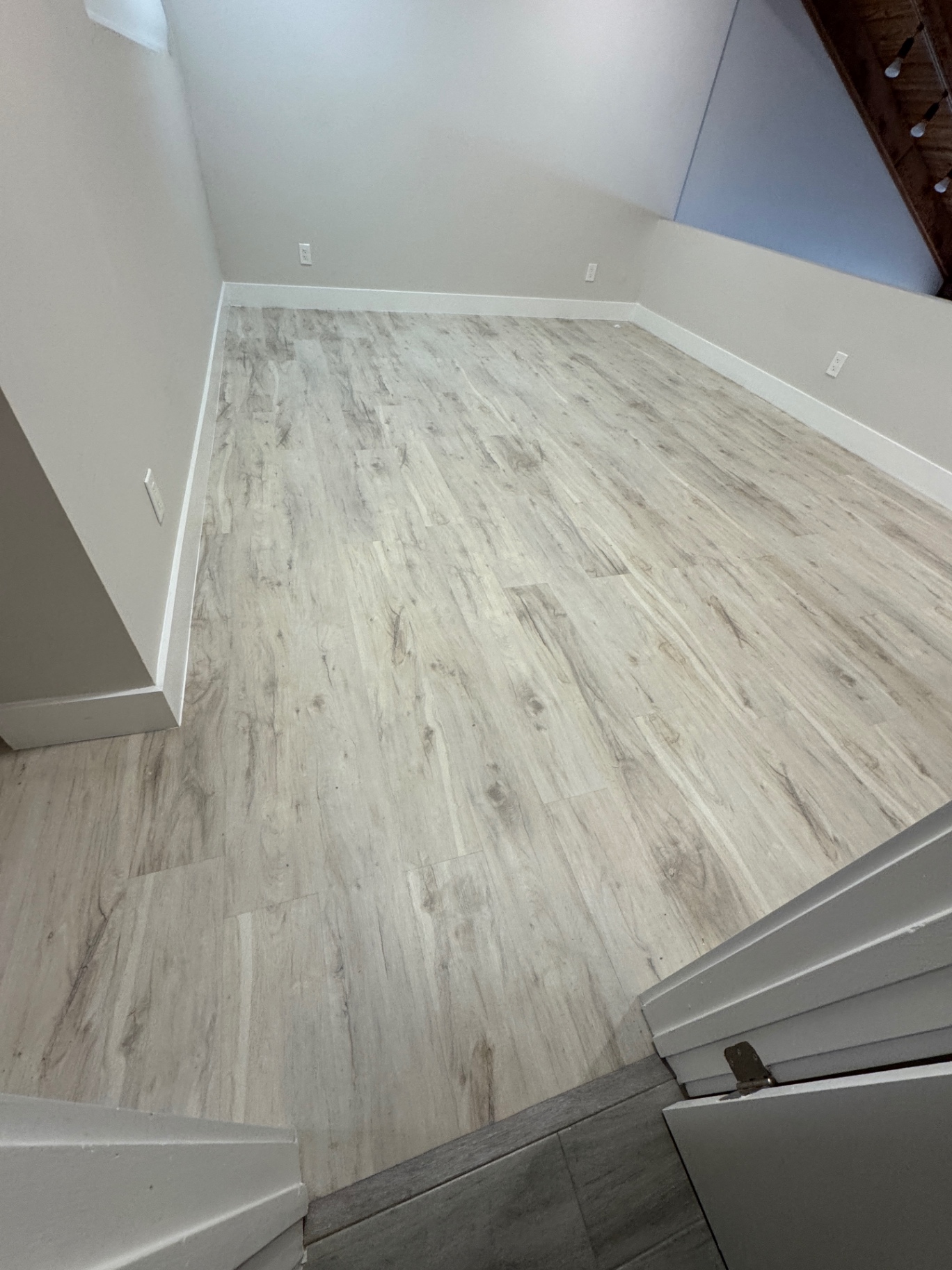 Finished room after corrective repair with continuous light wood-look flooring and clean white baseboards.