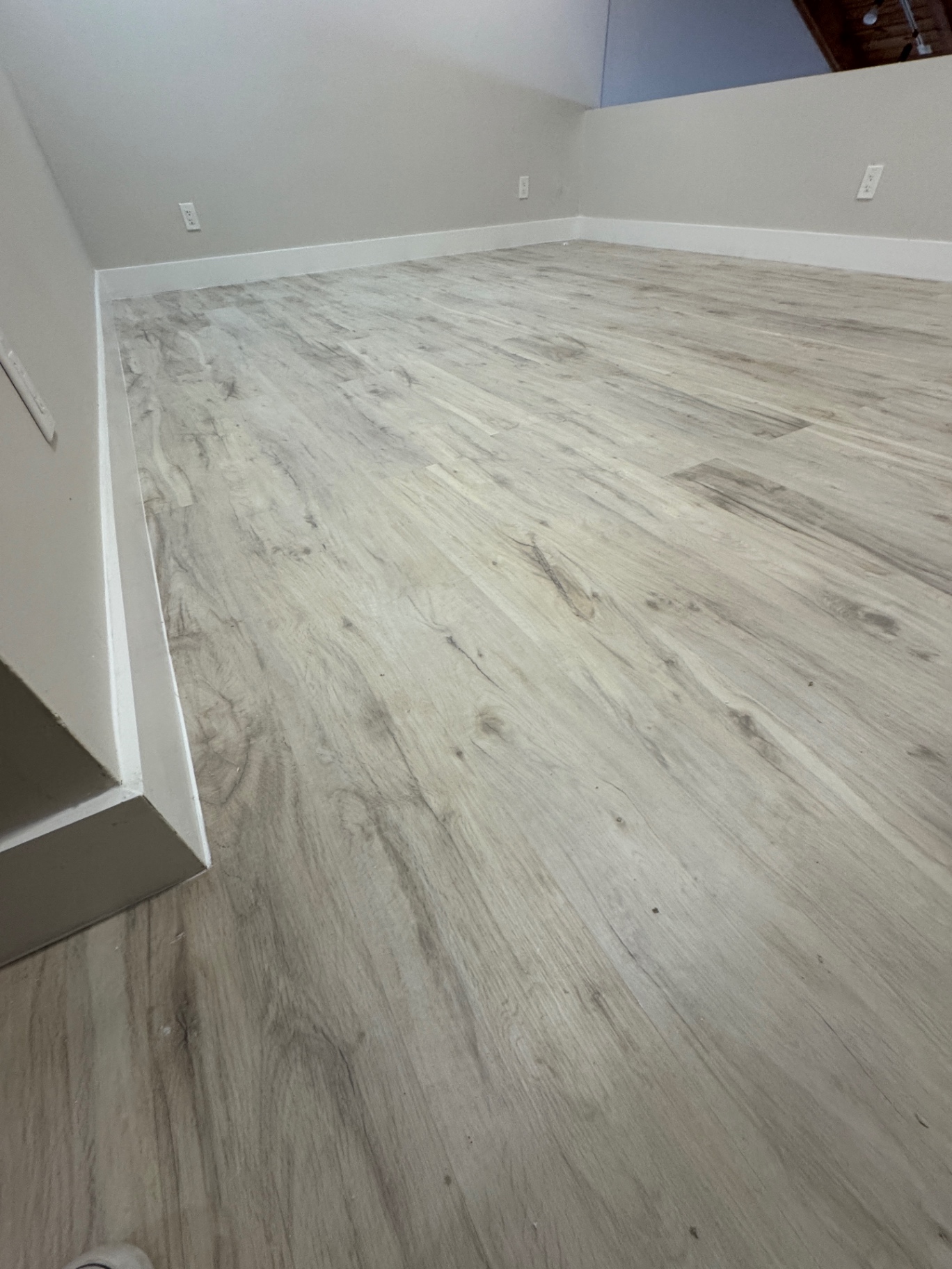 Corner view after repair showing clean plank alignment and white baseboards along the perimeter.
