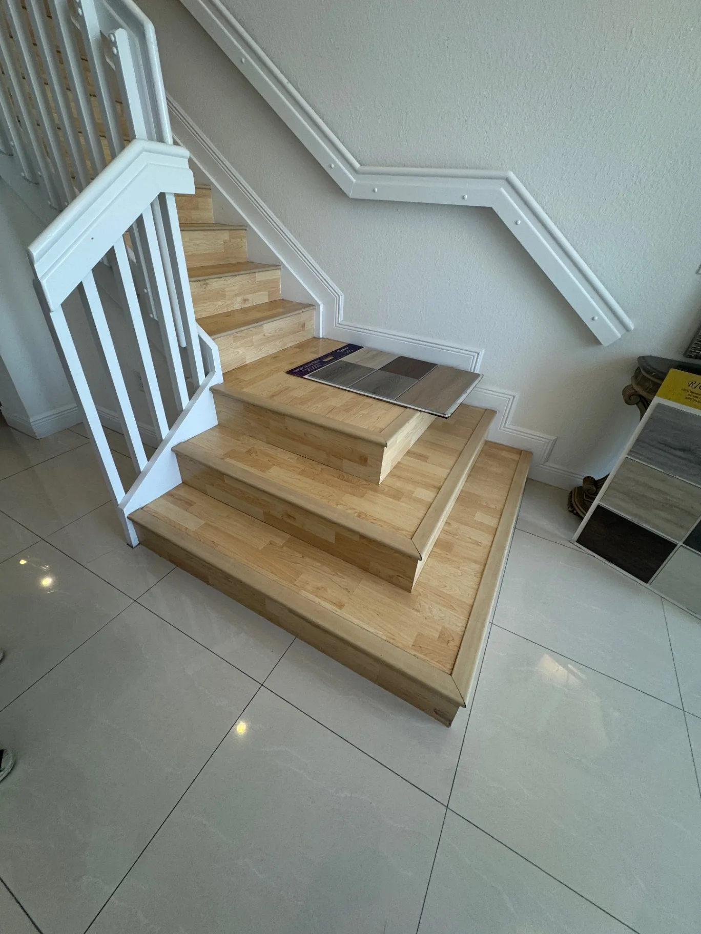 Small wood-look product sample placed on the newly finished lower steps during selection.