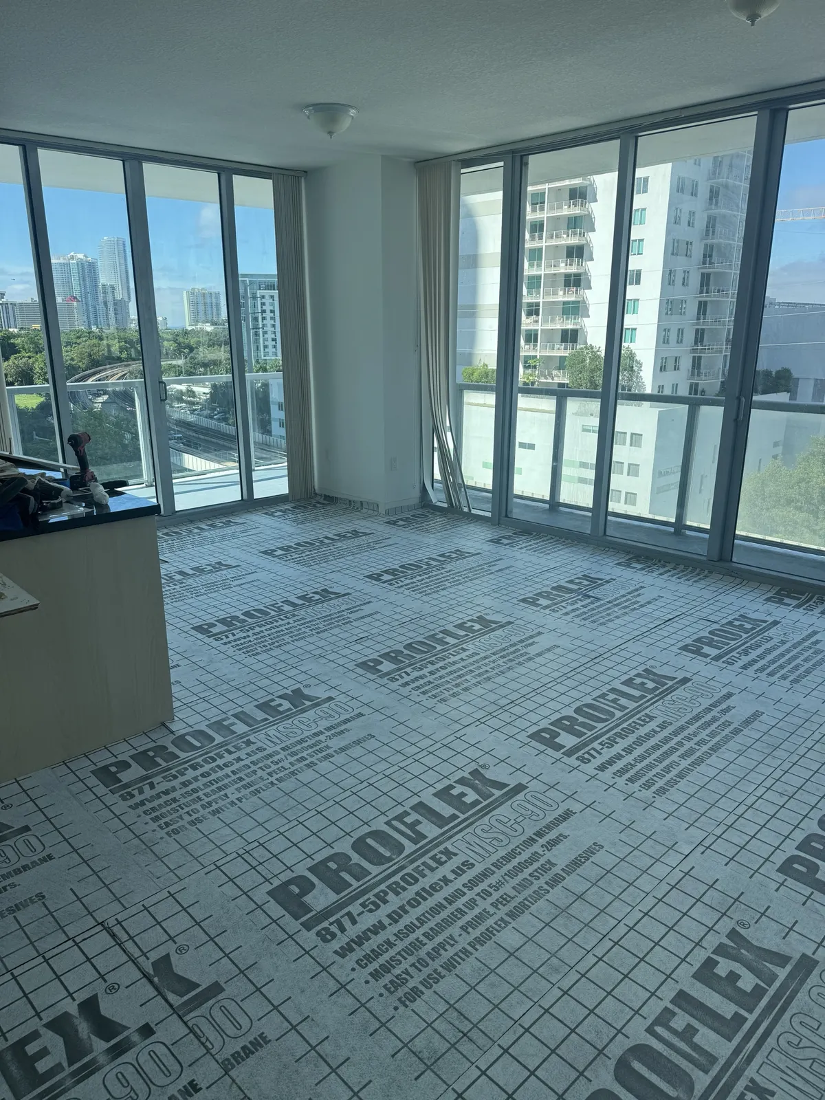 Second wide view of the completed living and dining area with finished Rio Novo Villa Arcadio vinyl flooring and the kitchen island visible in the background at Axis on Brickell.