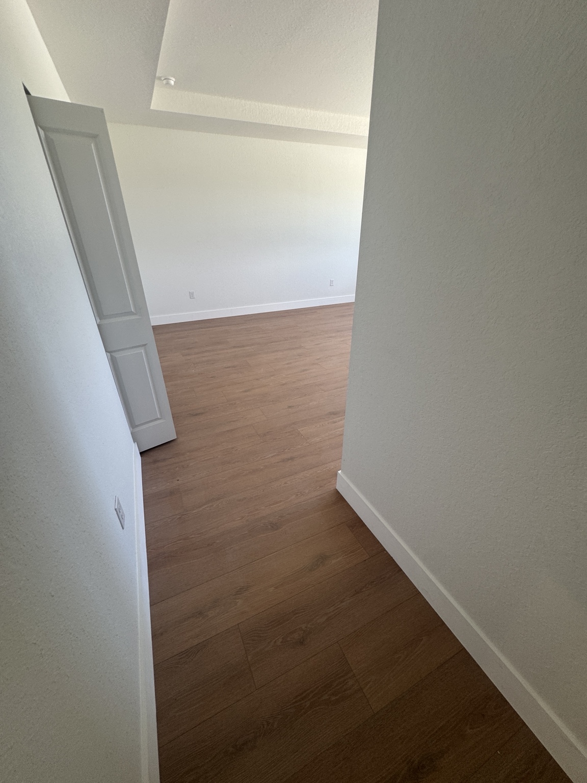 Primary room after installation — continuous warm oak laminate flooring