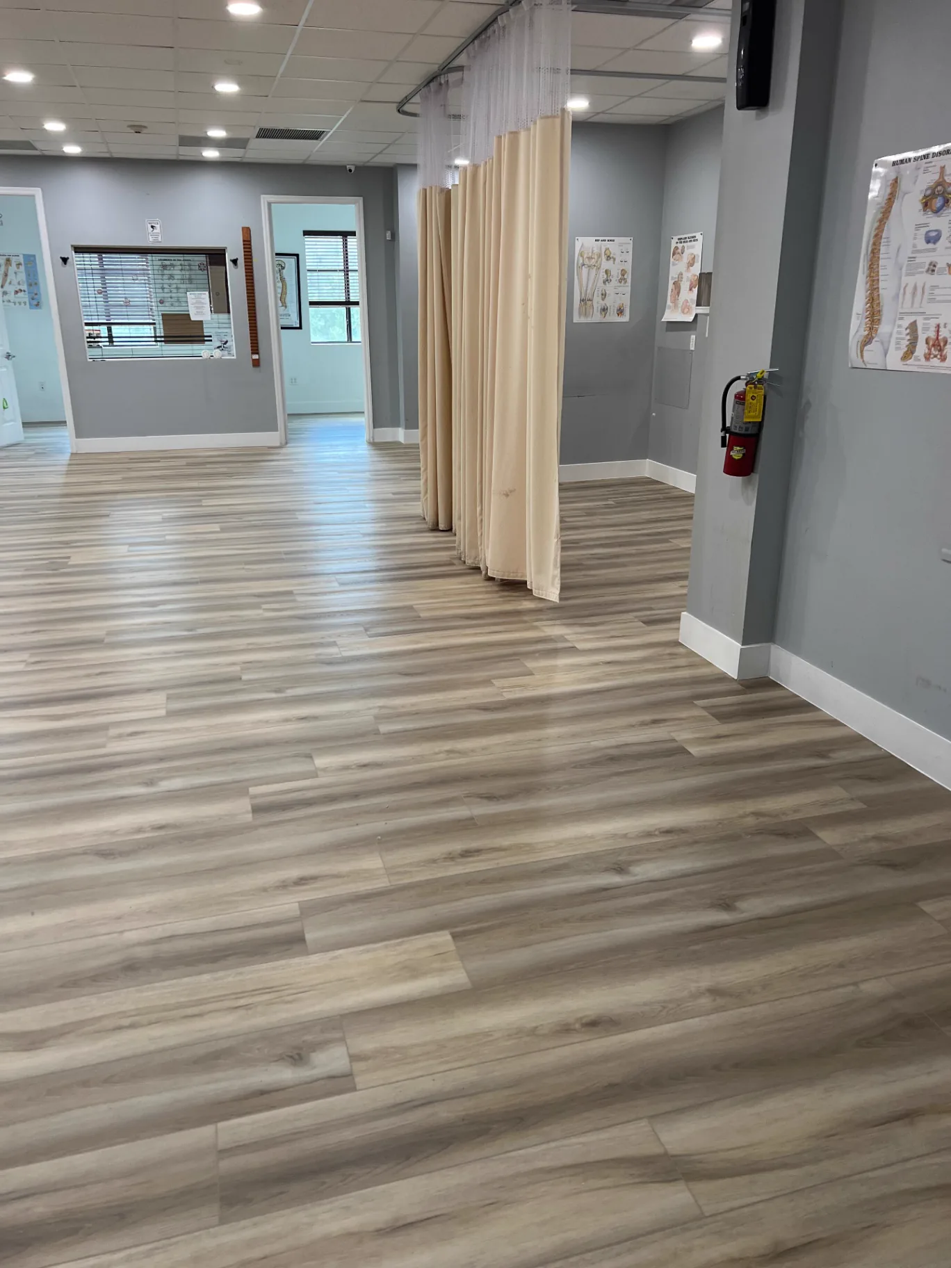 Wellness clinic in Miami with warm-toned wood-look commercial flooring installed by Colors Wood Floor Corp — treatment bay curtains in place.