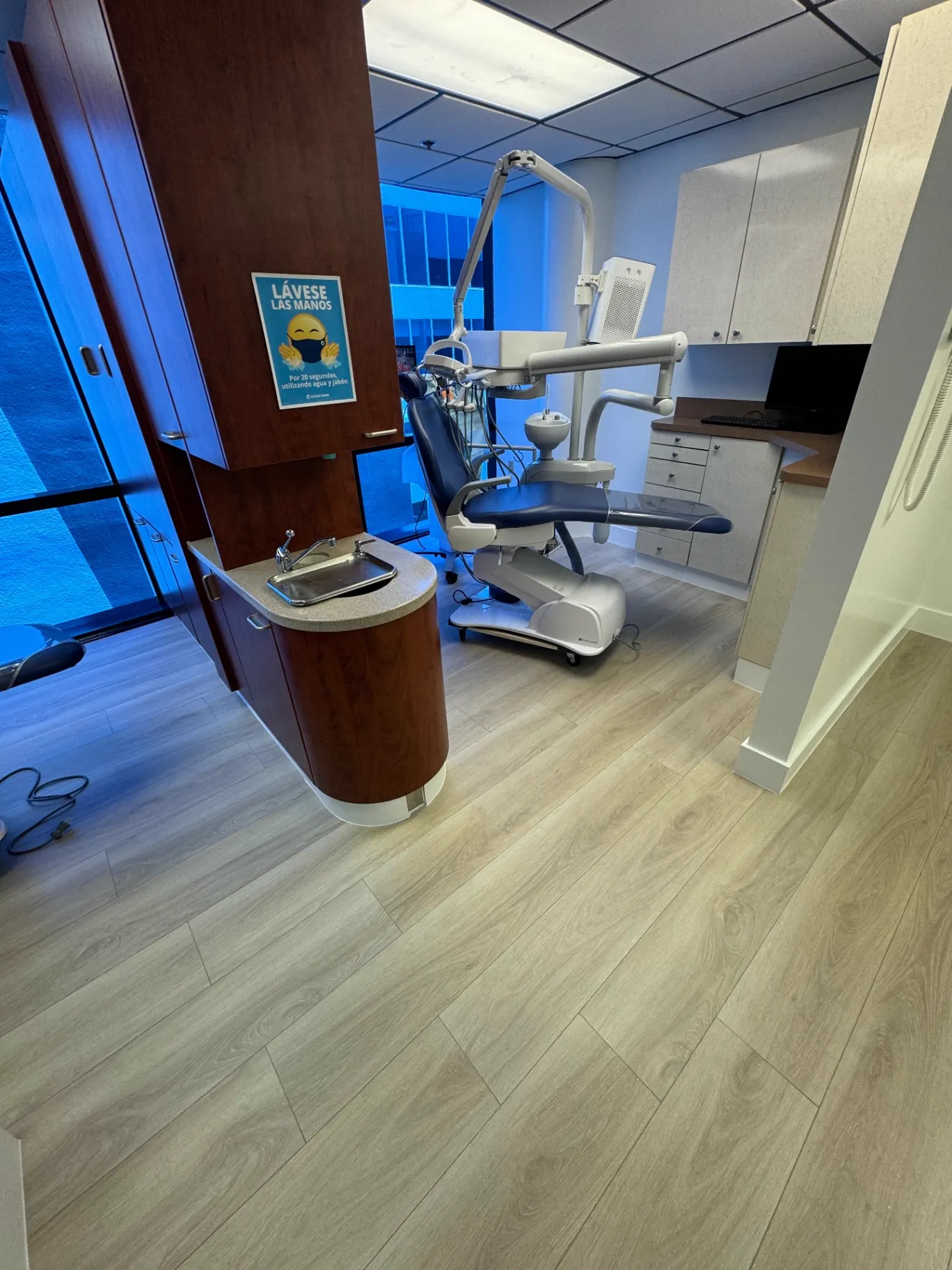 Completed single-chair dental operatory in Miami with light warm oak wood-look flooring installed by Colors Wood Floor Corp.