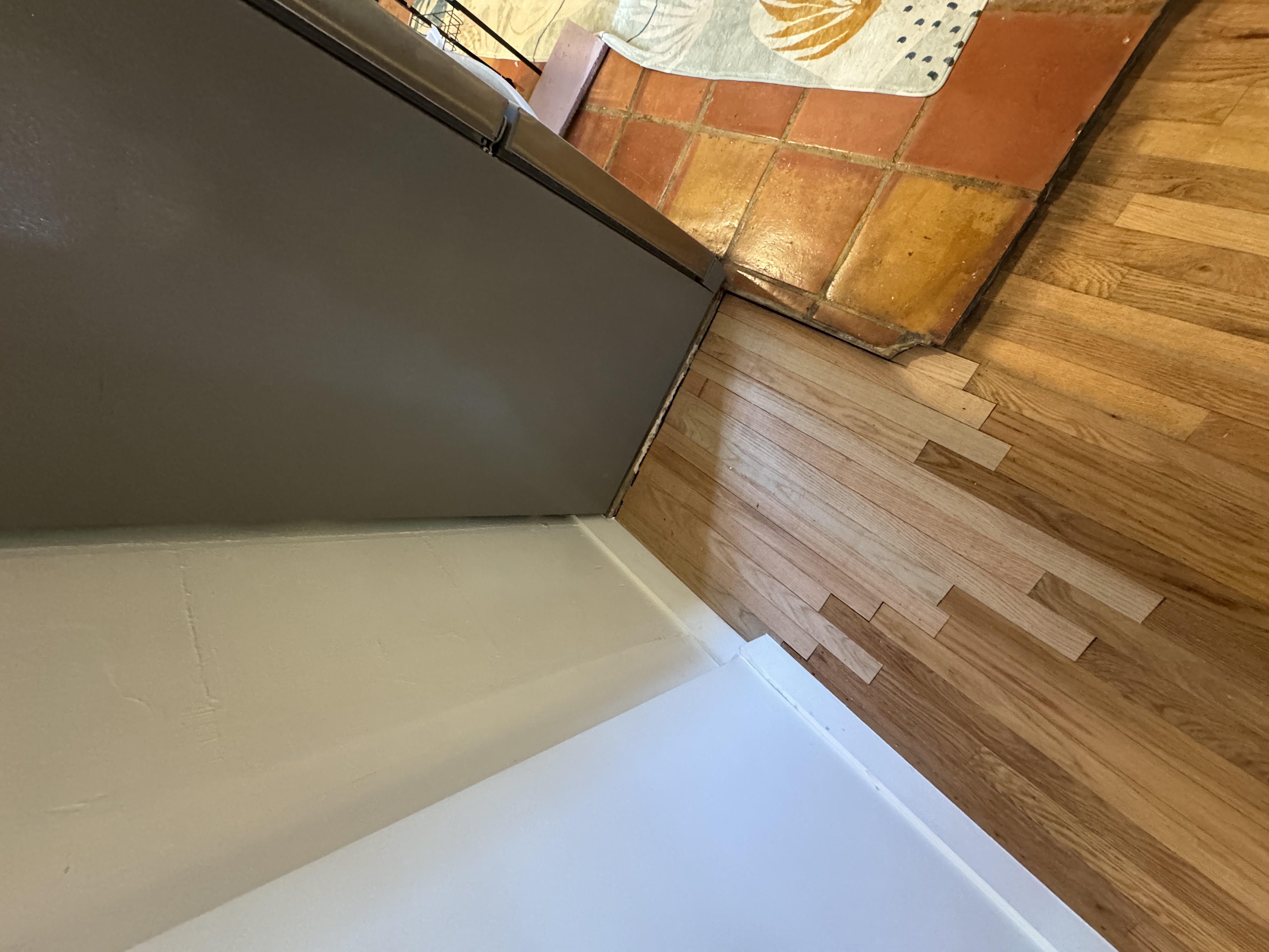 New matching hardwood boards installed and staggered into the existing floor pattern, filling the missing section.
