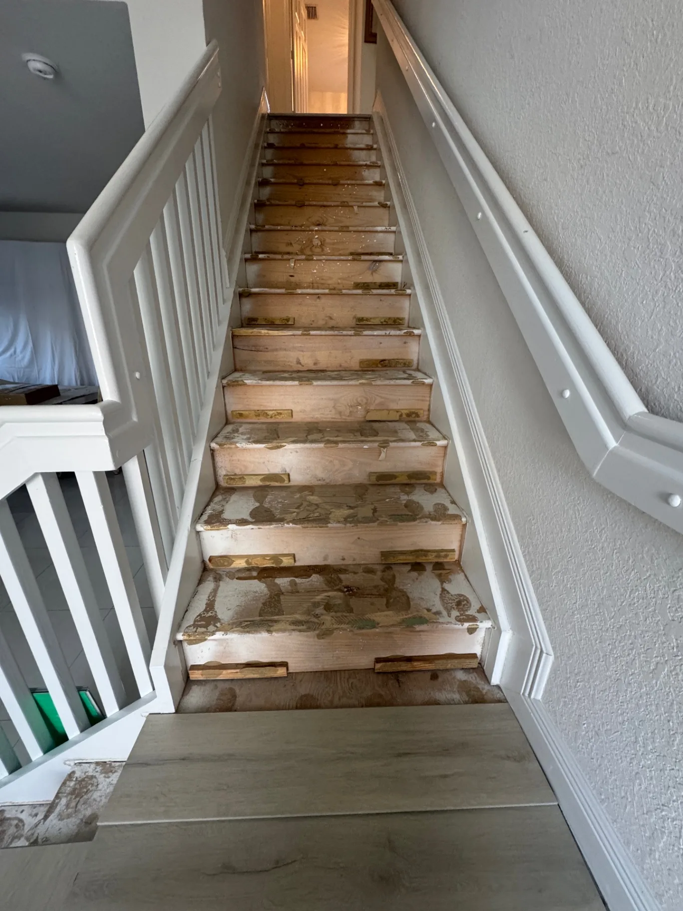Existing staircase with previous surface removed — bare treads and risers, view looking up before the new install.
