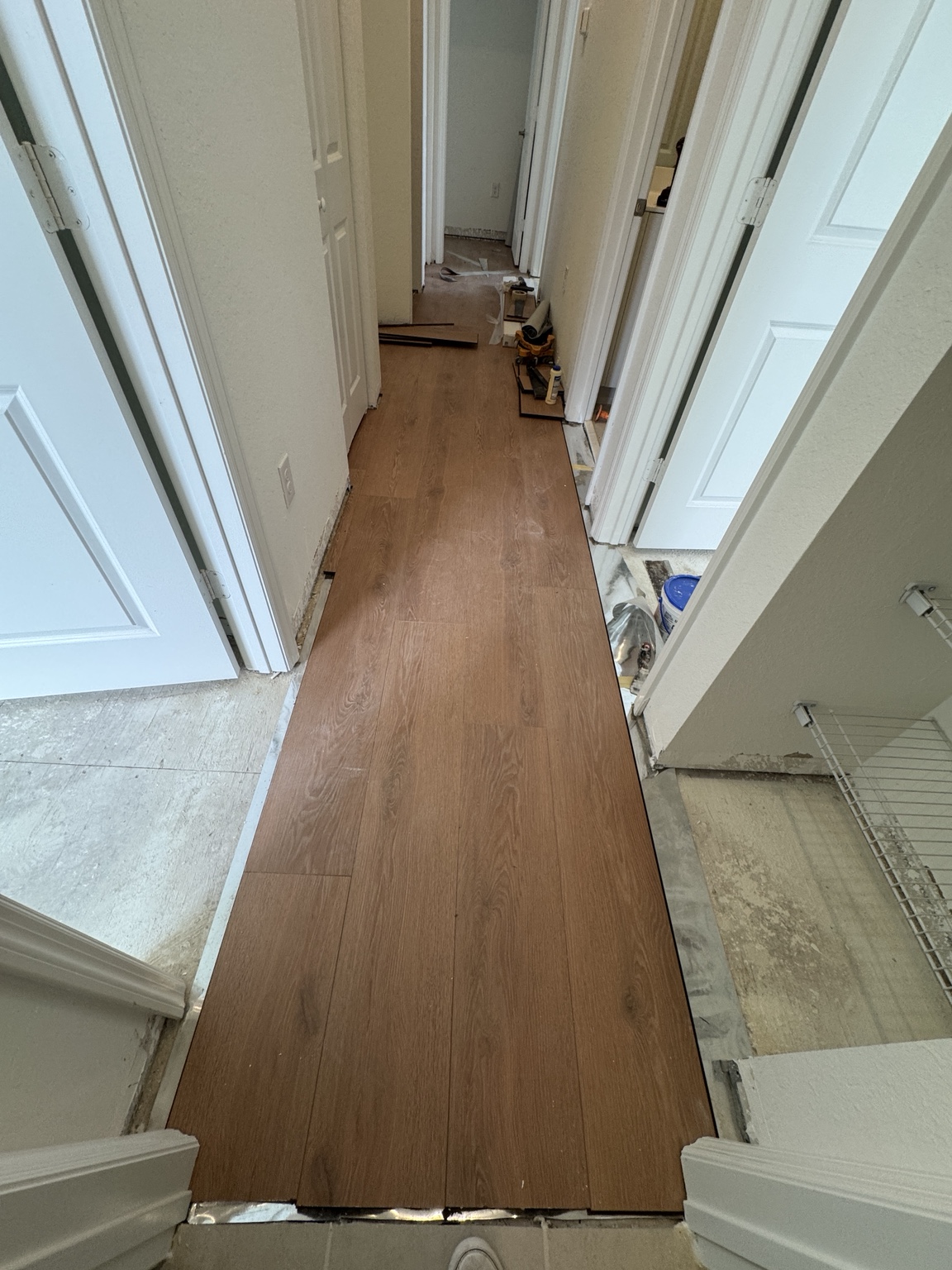 Warm oak laminate flooring installation in progress in a residential hallway
