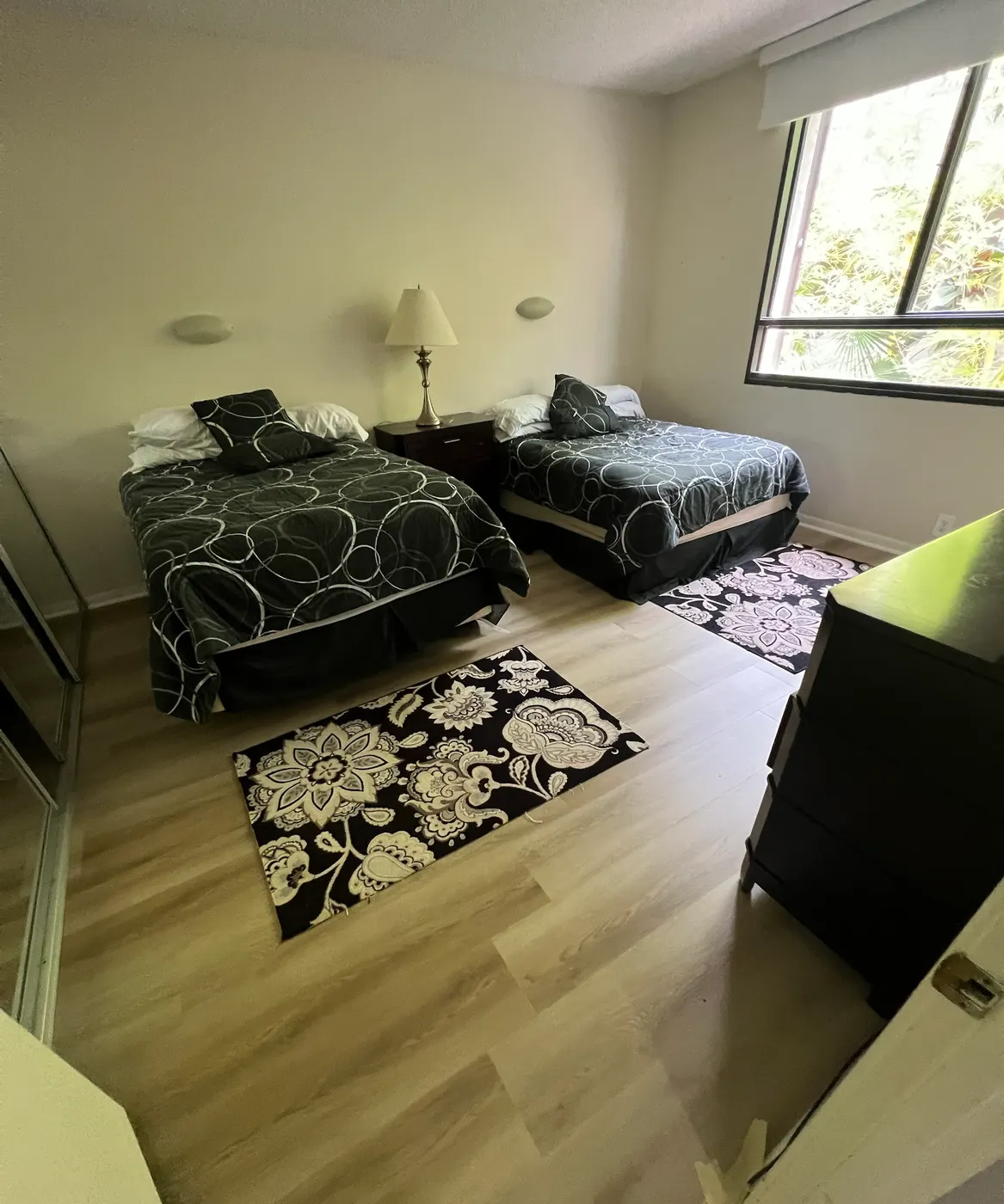 Guest bedroom with two beds and new light wood-look plank flooring installed by Colors Wood Floor