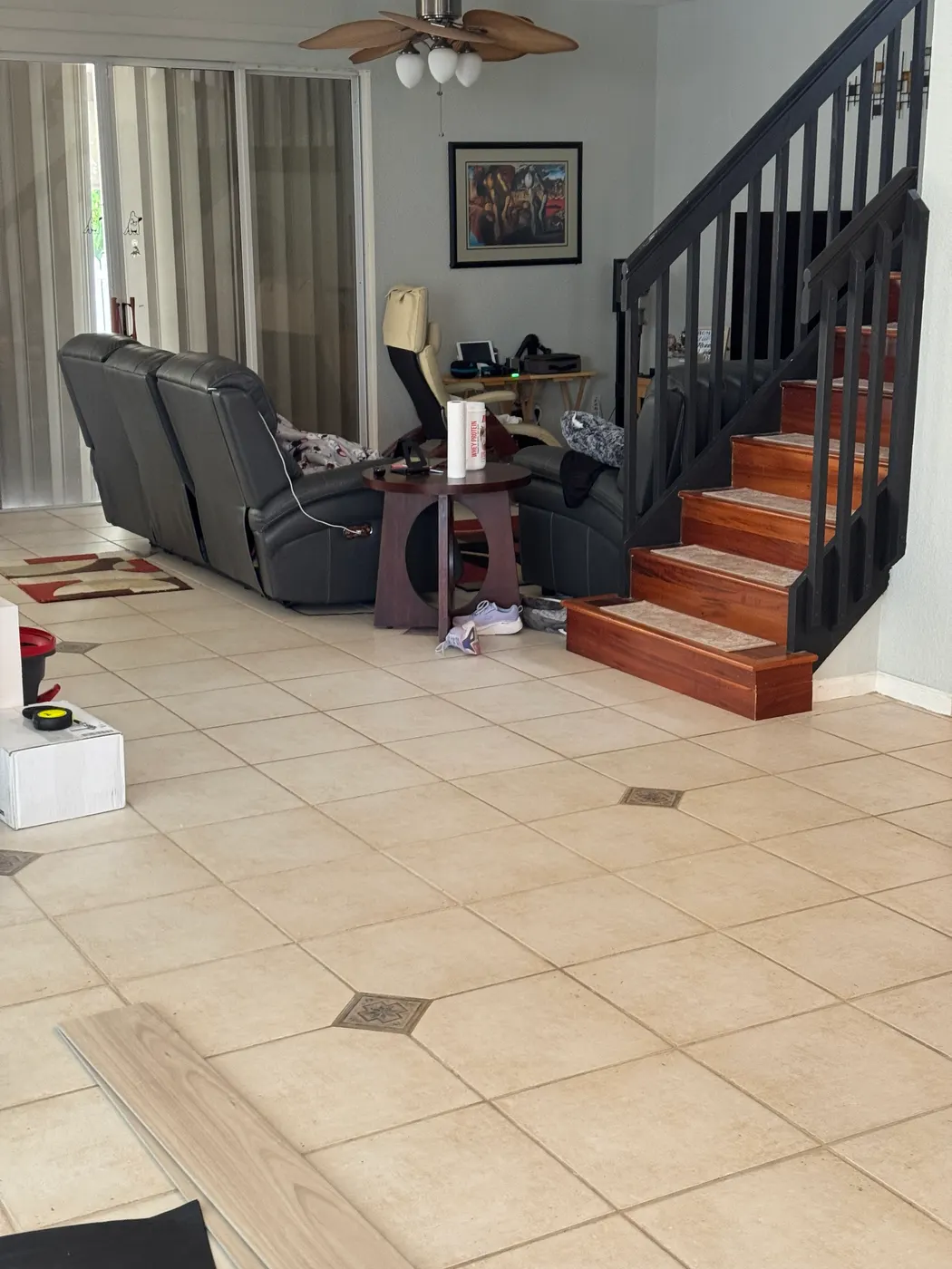 Living room before the flooring replacement, with the old ceramic tile floor and a sample plank laid on top