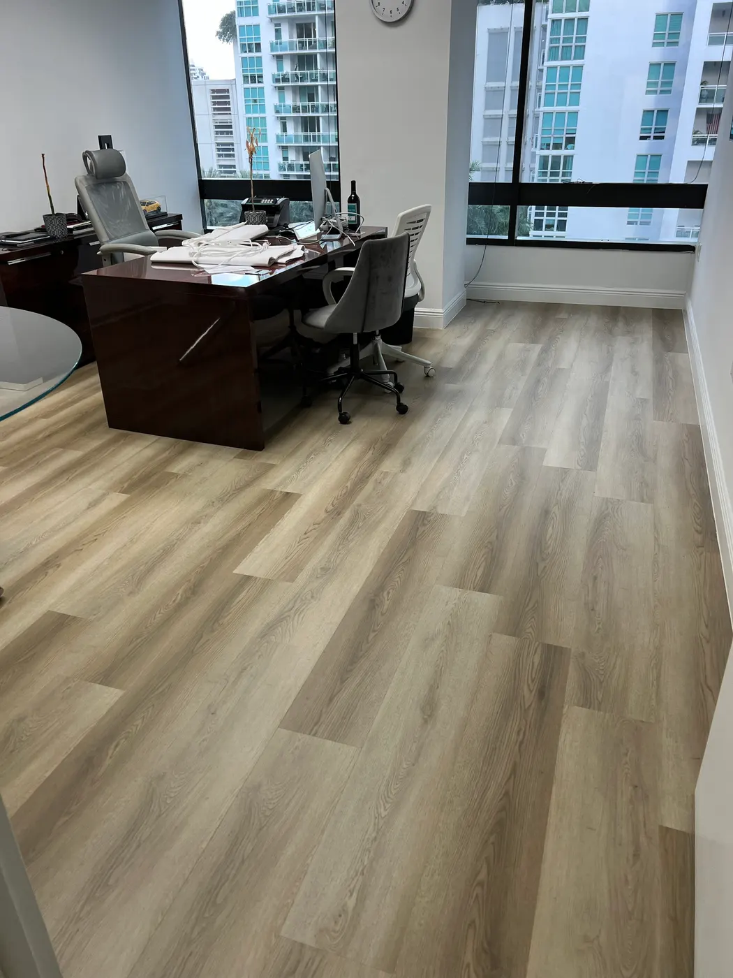 Private office with new light wood-look plank flooring and white baseboards, installed by Colors Wood Floor