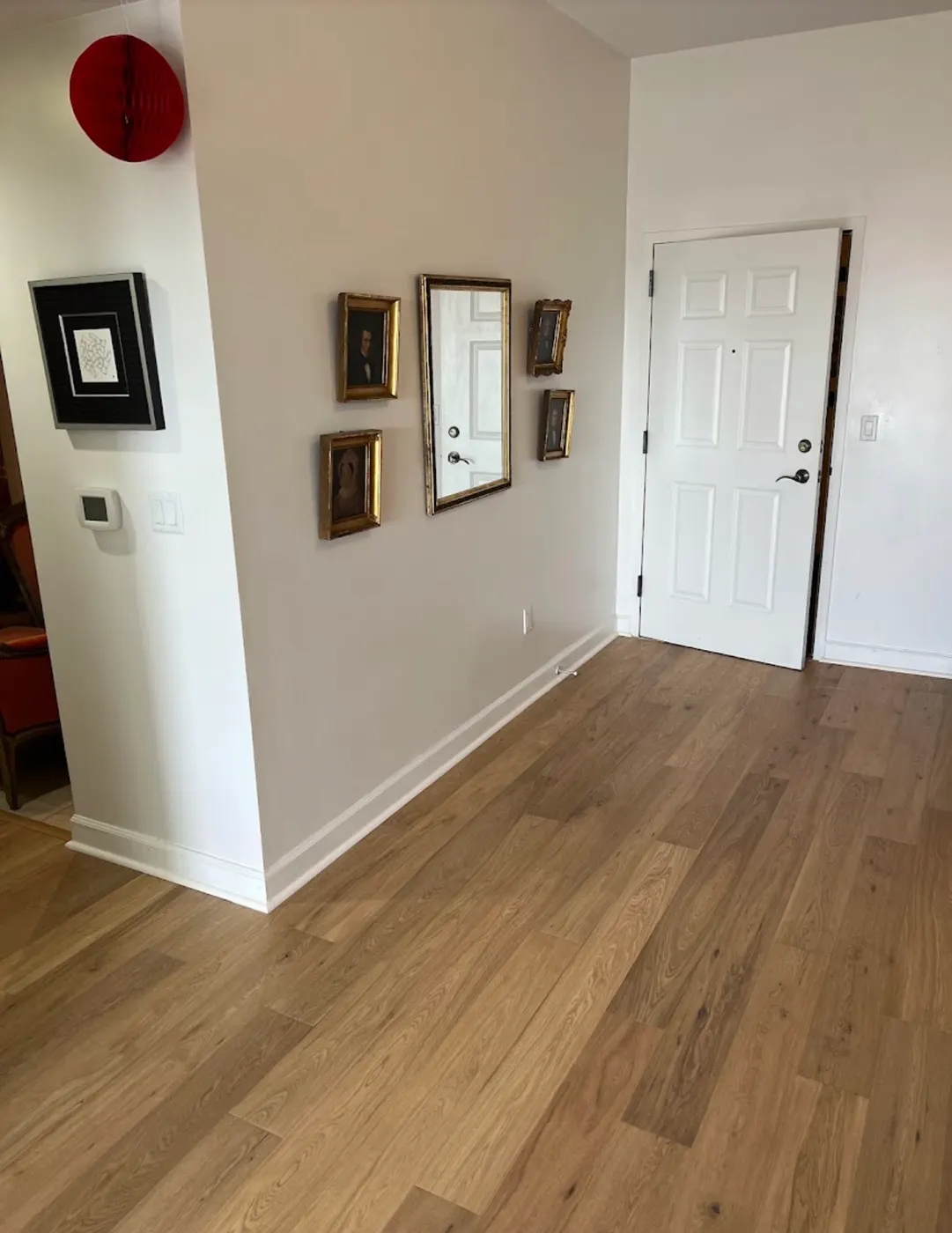 Wide-plank wood-look flooring in an entry area with new white baseboards, installed by Colors Wood Floor