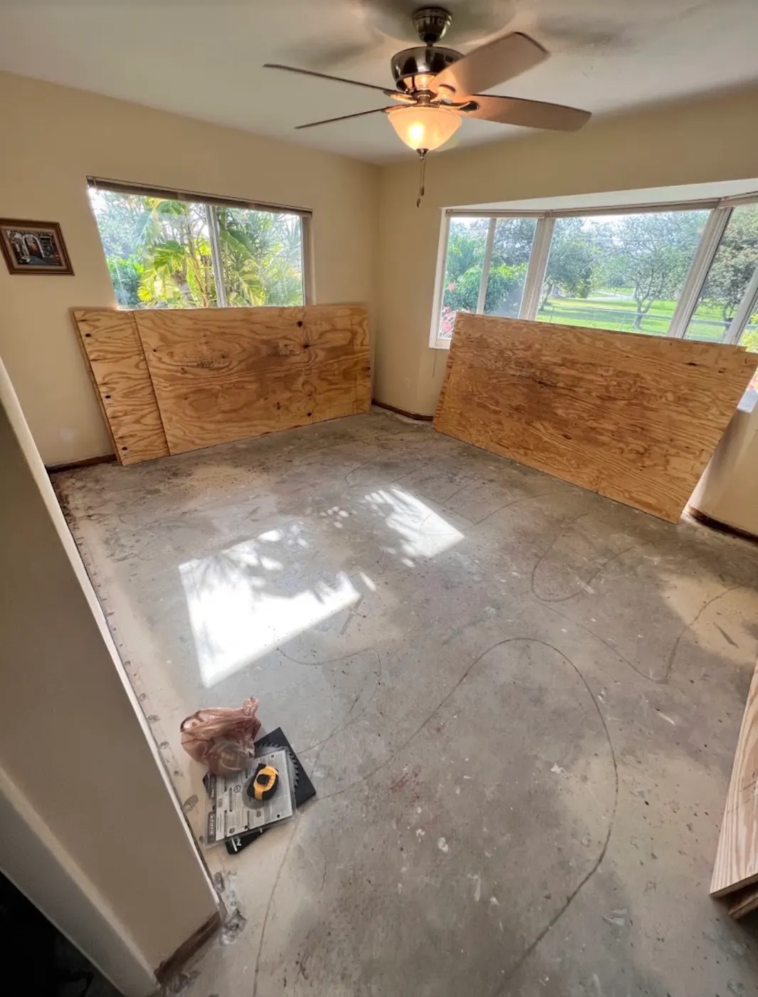Bedroom with the old flooring removed down to the concrete slab and plywood sheets ready for a new wood floor installation by Colors Wood Floor